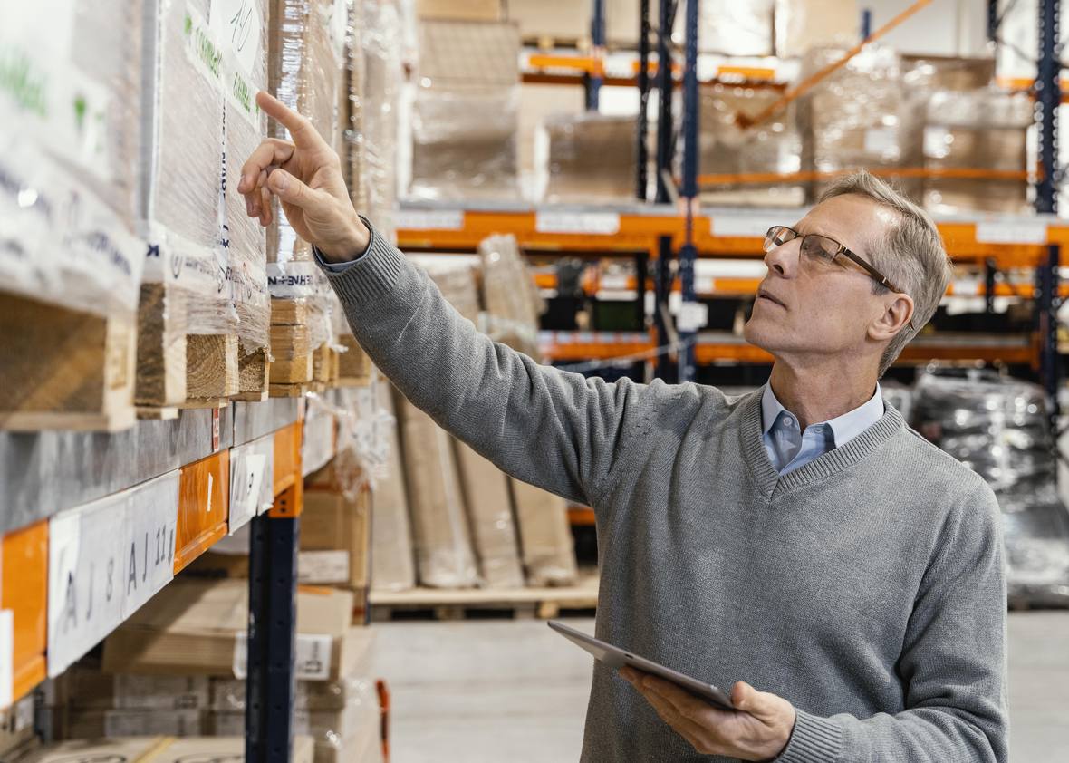 Store manager checking stock on shelving with a tablet in hand
